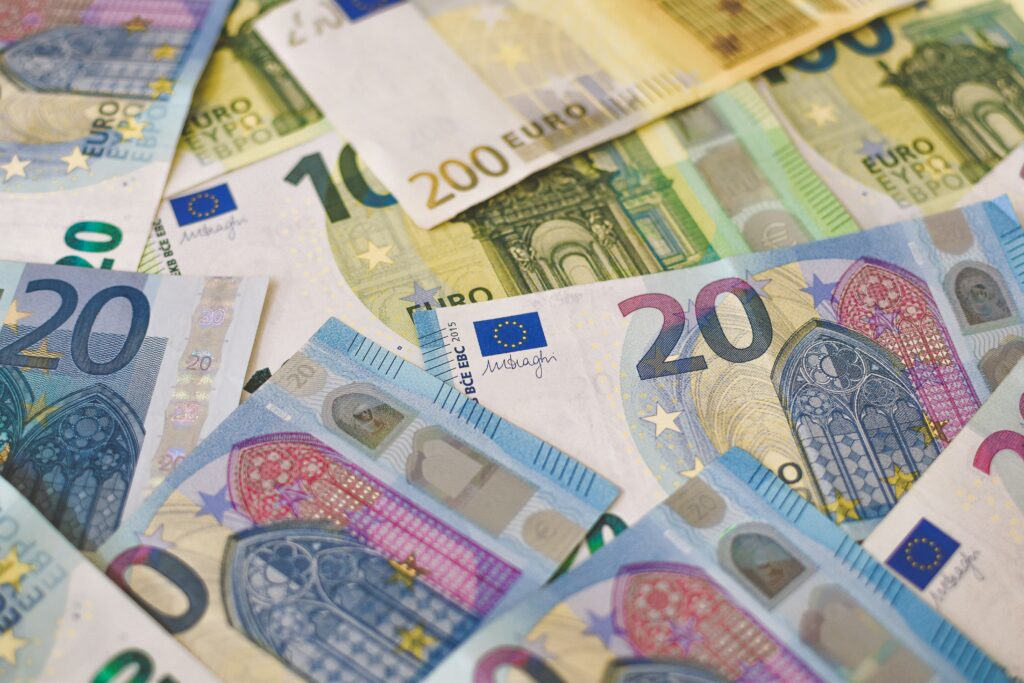 A close-up image of various euro banknotes scattered across a surface, including denominations of €10, €20, €50, €100, and €200, showcasing the coluorful designs and security features of the currency. This is the cash you will need to use in Greece